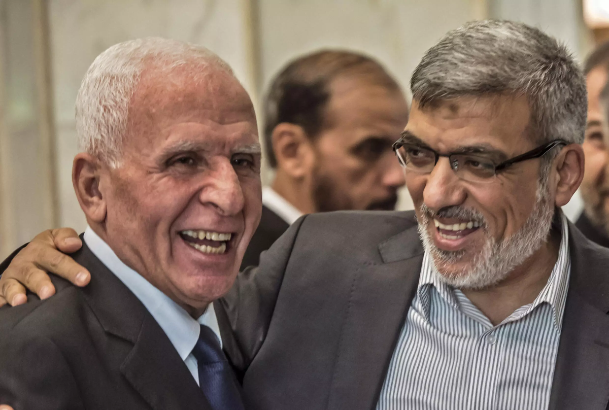 Azzam al-Ahmad (izq.), de Al Fatah, se ríe con Izzat al-Rishq (der.), del Hamás, tras la firma de un acuerdo de reconciliación en El Cairo el 12 de octubre de 2017. AFP - KHALED DESOUKI