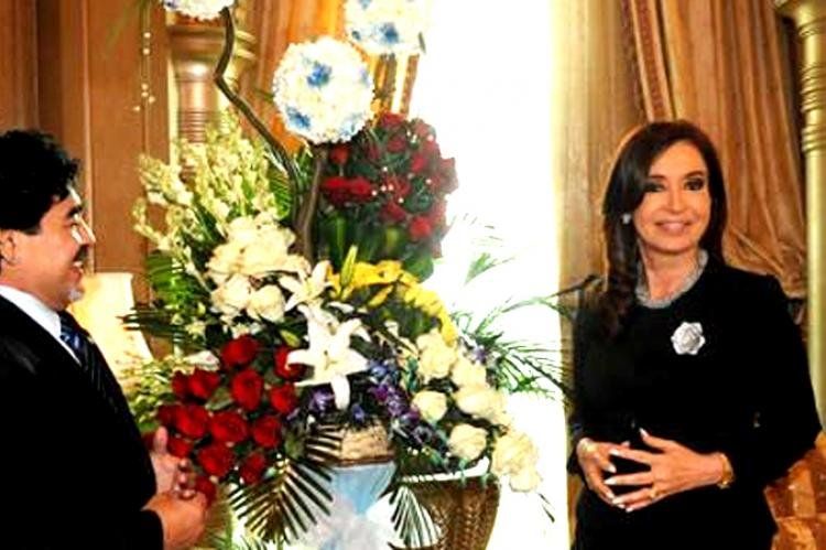Diego Armando Maradona, casi un taxi boy cultural, entrega un arreglo floral a Cristina Fernández de Kirchner.