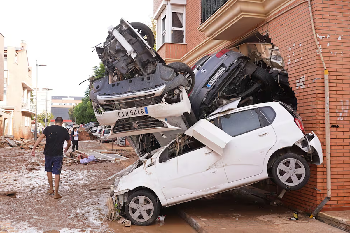 Un hombre camina junto a un grupo de coches amontonados tras las inundaciones en Massanassa, Valencia. Un hombre camina junto a un grupo de coches amontonados tras las inundaciones en Massanassa, Valencia.