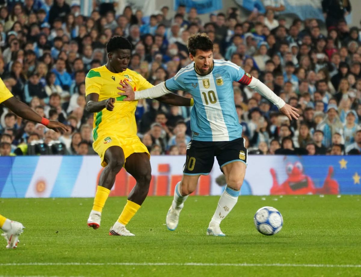 Lionel Messi disputa la pelota contra un futbolista de Benín, en su despedida en el Estadio Monumental