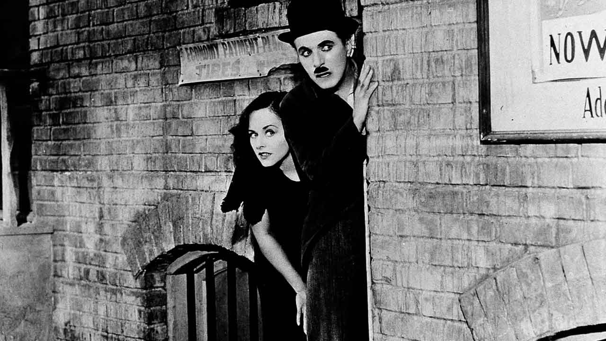 Acompañado de una joven huérfana, Charlot (el personaje de Charles Chaplin) enfrenta las adversidades con su característico optimismo. Acompañado de una joven huérfana, Charlot (el personaje de Charles Chaplin) enfrenta las adversidades con su característico optimismo.