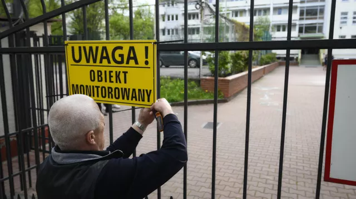 Un miembro del ayuntamiento de Polonia cuelga se&ntilde;al de advertencia en la escuela de la embajada de Rusia en Varsovia.