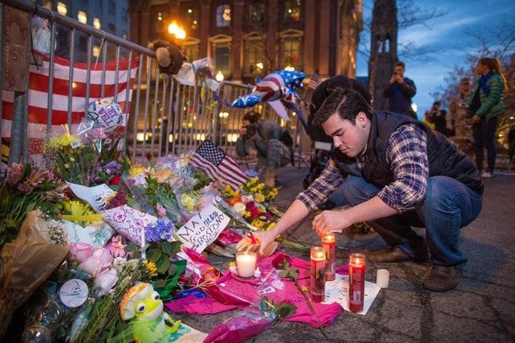 Sam Galvin, de West Roxbury, enciende velas en un homenaje por las víctimas, en Boylston Street, Boston (Foto Boston Globe).