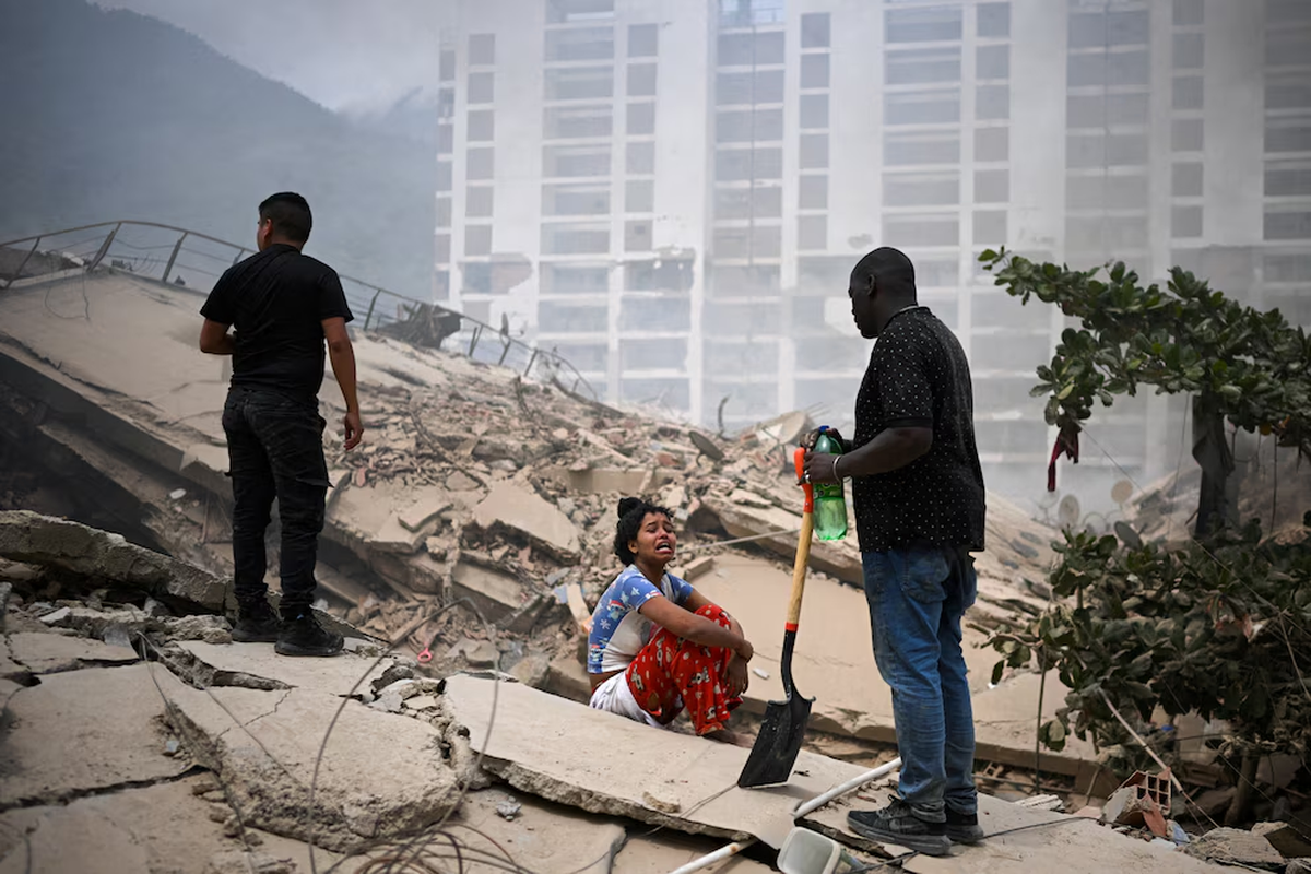 Una mujer observa cómo se busca a posibles víctimas entre los escombros de los edificios derrumbados, tras los terremotos ocurridos en La Guaira, en Venezuela. 25 de junio de 2026. | REUTERS/Gaby Oraa Una mujer observa cómo se busca a posibles víctimas entre los escombros de los edificios derrumbados, tras los terremotos ocurridos en La Guaira, en Venezuela. 25 de junio de 2026. | REUTERS/Gaby Oraa