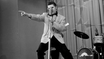 Un día de 1956, Elvis Presley sacudió la televisión con Hound Dog y revolucionó la música con un meneo de pelvis que escandalizó y enamoró a todo EE.UU. Un día de 1956, Elvis Presley sacudió la televisión con Hound Dog y revolucionó la música con un meneo de pelvis que escandalizó y enamoró a todo EE.UU.