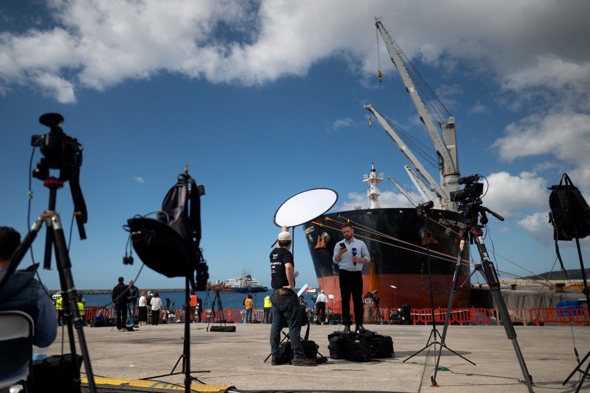 Periodistas trabajan en el puerto de Granadilla de Abona, en Tenerife, con el MV Hondius de fondo. Espa&ntilde;a asegur&oacute; que tom&oacute; todas las medidas para evitar nuevos contagios de hantavirus durante la repatriaci&oacute;n de pasajeros.