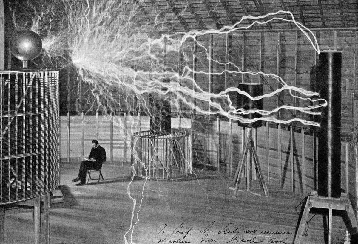Una descarga cruza desde una bobina central a otra del laboratorio de Colorado Springs mientras Tesla está sentado en su silla en 1899. | GENTILEZA MUSEO NIKOLA TESLA Una descarga cruza desde una bobina central a otra del laboratorio de Colorado Springs mientras Tesla está sentado en su silla en 1899. | GENTILEZA MUSEO NIKOLA TESLA