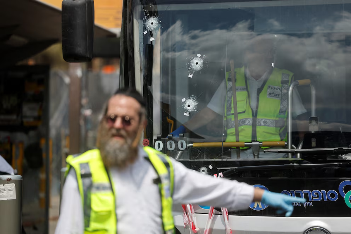 La gente inspecciona un autobús con agujeros de bala en el lugar donde se produjo el ataque a tiros en las afueras de Jerusalén. | GENTILEZA REUTERS La gente inspecciona un autobús con agujeros de bala en el lugar donde se produjo el ataque a tiros en las afueras de Jerusalén. | GENTILEZA REUTERS