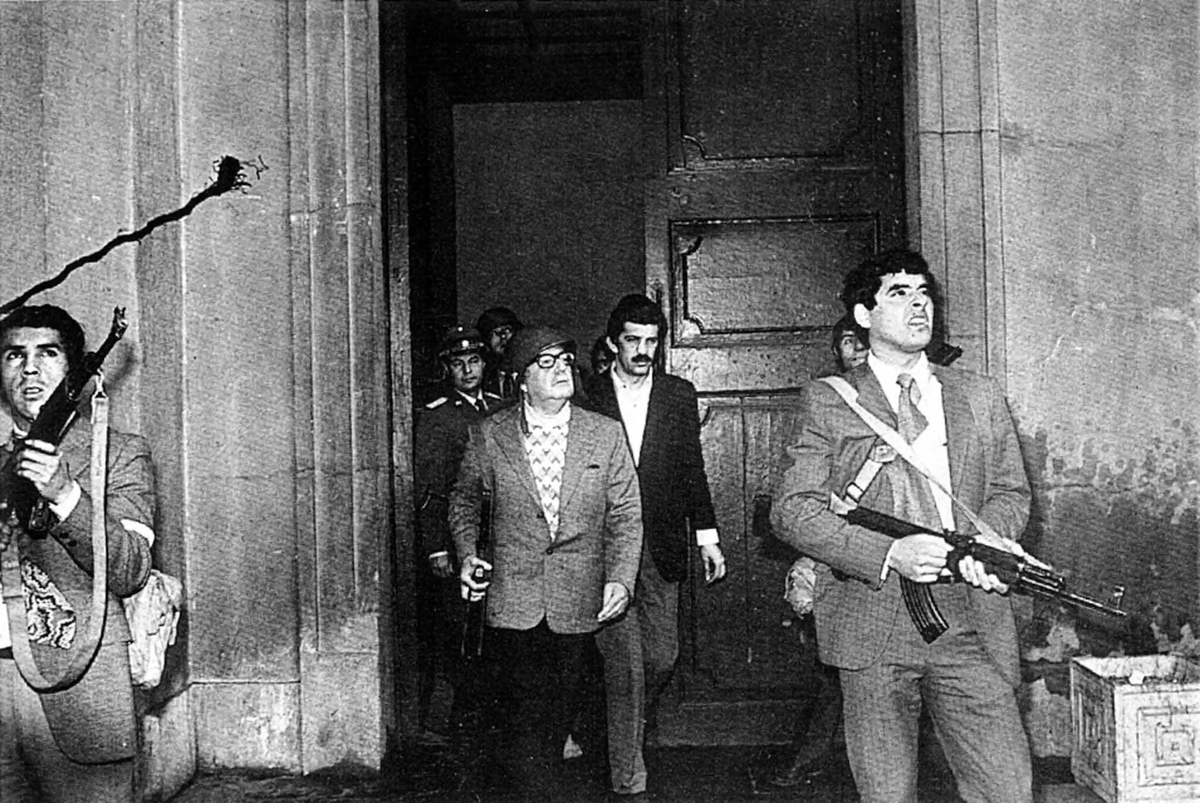 El presidente Salvador Allende, con un casco, junto a guardaespaldas mientras las fuerzas de Pinochet continuaban su asedio armado contra el palacio presidencial.Credit...Reuters