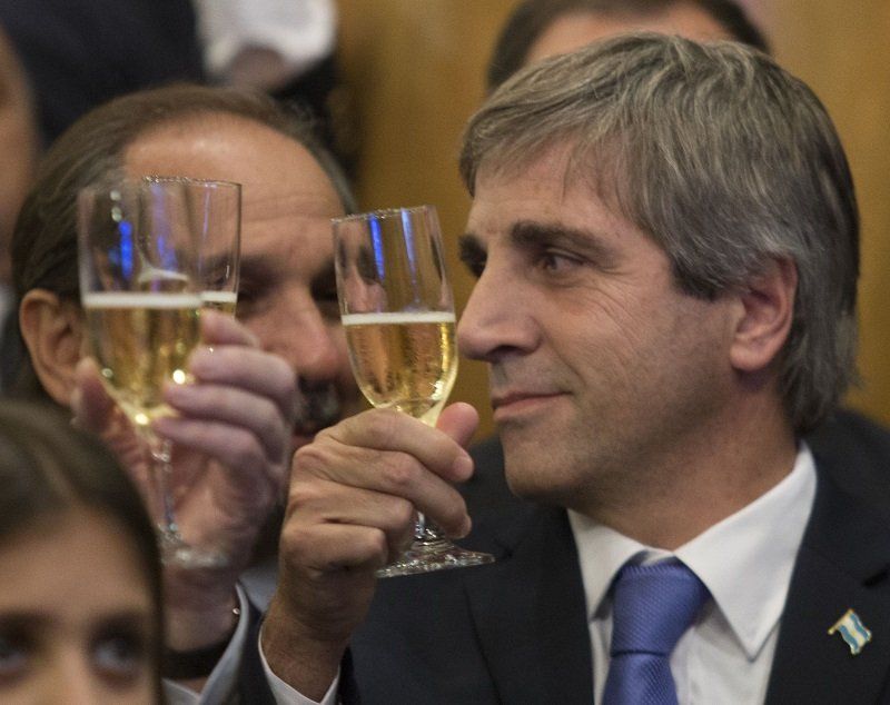 Ministro Luis Caputo brinda con su primo Nicolás Caputo (oculto por una copa de champagne).