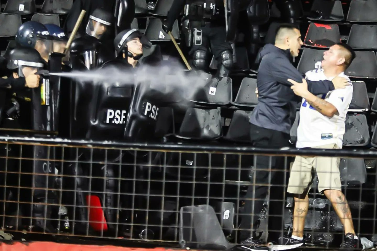 En el medio Riquelme, de un lado un hincha furioso, del otro un policía lanzando gas pimienta sobre ambos. En el medio Riquelme, de un lado un hincha furioso, del otro un policía lanzando gas pimienta sobre ambos.