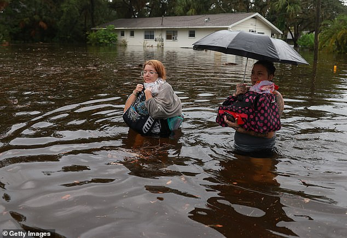 Makatla Ritchter (izq.) y su madre, Keiphra Line, atraviesan las aguas de la inundación después de tener que evacuar su casa. Makatla Ritchter (izq.) y su madre, Keiphra Line, atraviesan las aguas de la inundación después de tener que evacuar su casa.