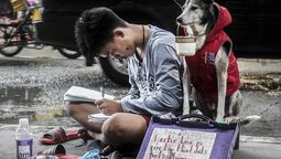 Humanidad en riesgo. Un ícono en la imagen: filipino Eddie Aquino, de 16 años, junto a su perro Black Jack. Él intenta estudiar mientras su perro pide dinero.