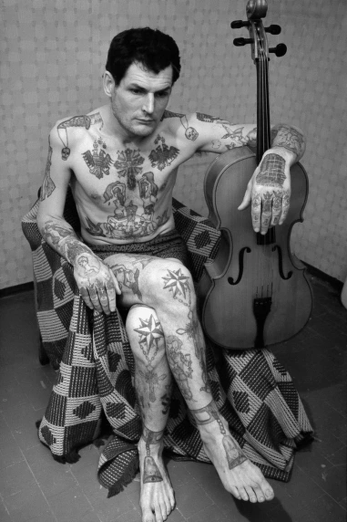 Calaveras, huesos, dagas en hombros, estrellas, campanas en pies = asesino sentenciado a cadena perpetua, mató a otro preso, anti policía (estrellas en rodillas).