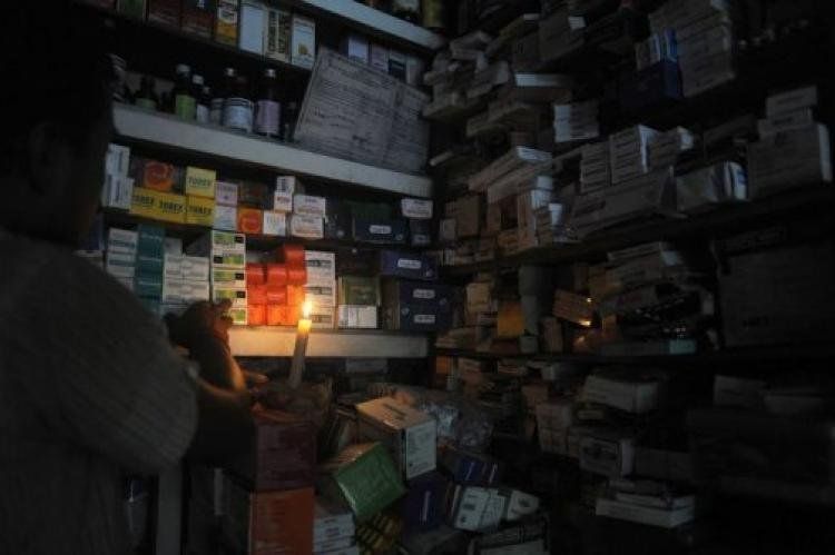Un farmacéutico de la ciudad india de Siliguri busca unas medicinas ayudándose de una vela (AFP, Diptendu Dutta)