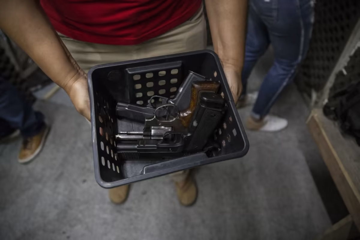 Un instructor sostiene una canasta de pistolas para los miembros que ingresan al campo de tiro de un club de tiro de Río de Janeiro