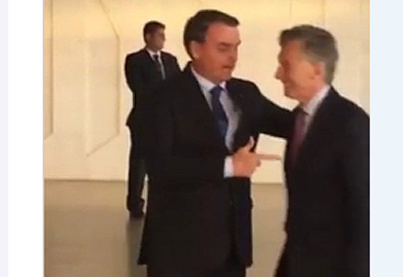 Bolsonaro imita a un arma con su mano y le apunta a Macri.... (Foto: Captura de video).
