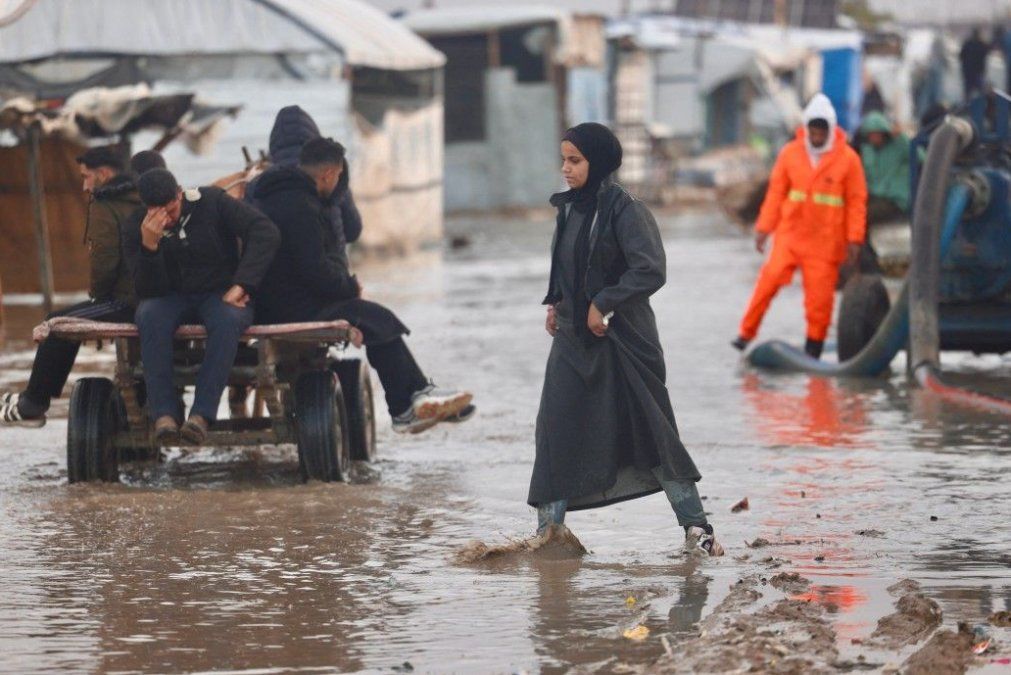 Una mujer palestina desplazada camina sobre las aguas que inundan el campamento de refugiados de Al-Mawasi, en el sur de la Franja de Gaza, el 29/12/2025. Una mujer palestina desplazada camina sobre las aguas que inundan el campamento de refugiados de Al-Mawasi, en el sur de la Franja de Gaza, el 29/12/2025.